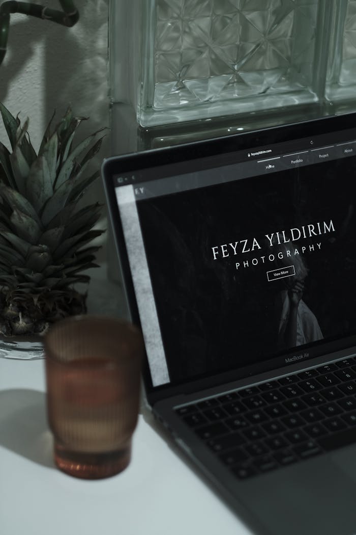 An aesthetically pleasing workspace featuring a laptop with a photographers website, surrounded by minimalist decor.